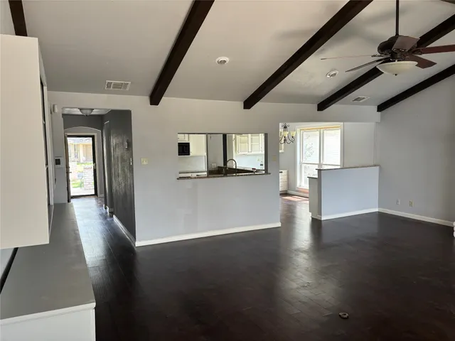 a view of a hallway with wooden floor and a kitchen