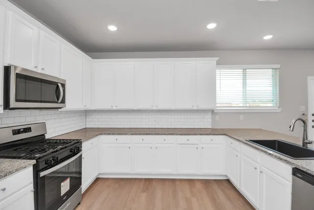 a view of a kitchen with a sink a stove top oven and cabinets