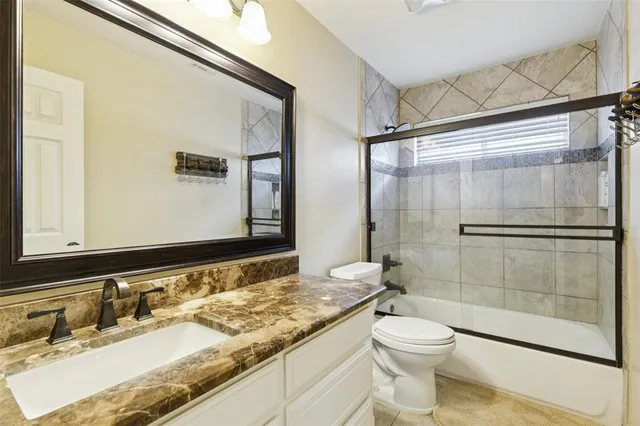 a bathroom with a granite countertop sink toilet and shower