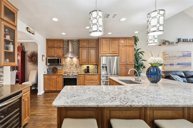 a kitchen with stainless steel appliances granite countertop a sink refrigerator and cabinets