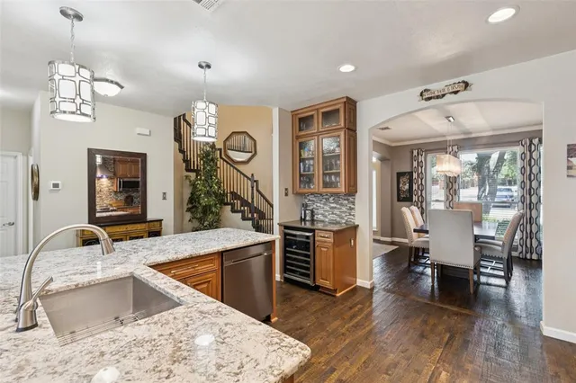 a kitchen with stainless steel appliances granite countertop a sink dishwasher a stove and a dining table with wooden floor