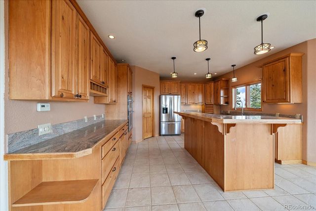 a kitchen with kitchen island granite countertop a sink counter top space appliances and cabinets
