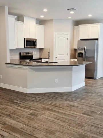 a large kitchen with stainless steel appliances granite countertop a stove a sink and a microwave