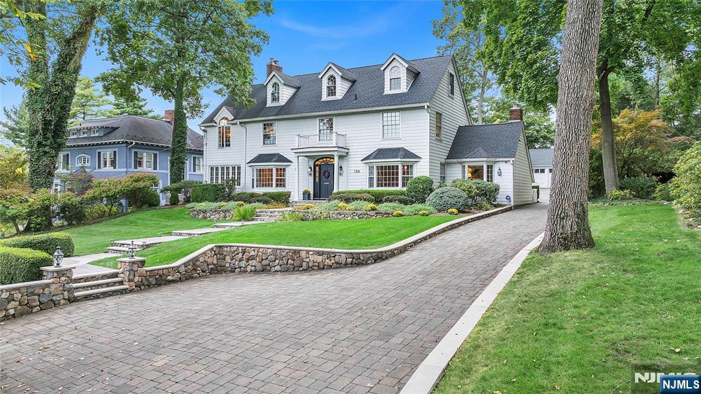 a view of a white house with a big yard plants and large trees