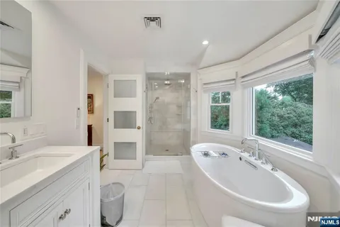 a spacious bathroom with a tub sink toilet and mirror