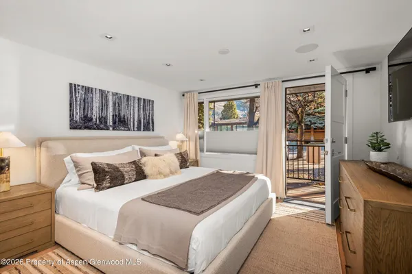 a bedroom with a large bed and a flat tv screen on dresser