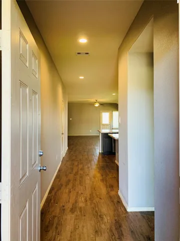 a view of a hallway with wooden floor and a bathroom