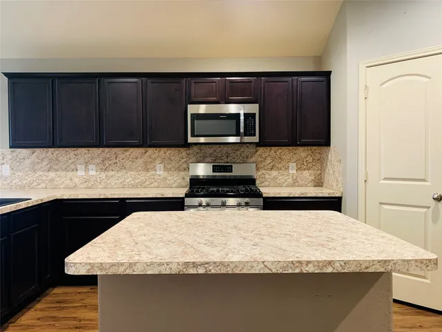 a kitchen with granite countertop wood cabinets stainless steel appliances and a sink