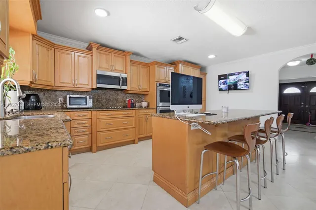 a kitchen with stainless steel appliances granite countertop a refrigerator a stove a sink a dining table and chairs with wooden floor