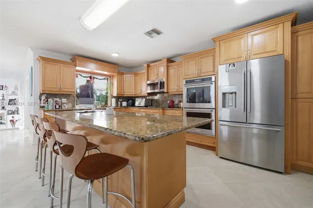 a kitchen with stainless steel appliances granite countertop a refrigerator a stove a sink a dining table and chairs