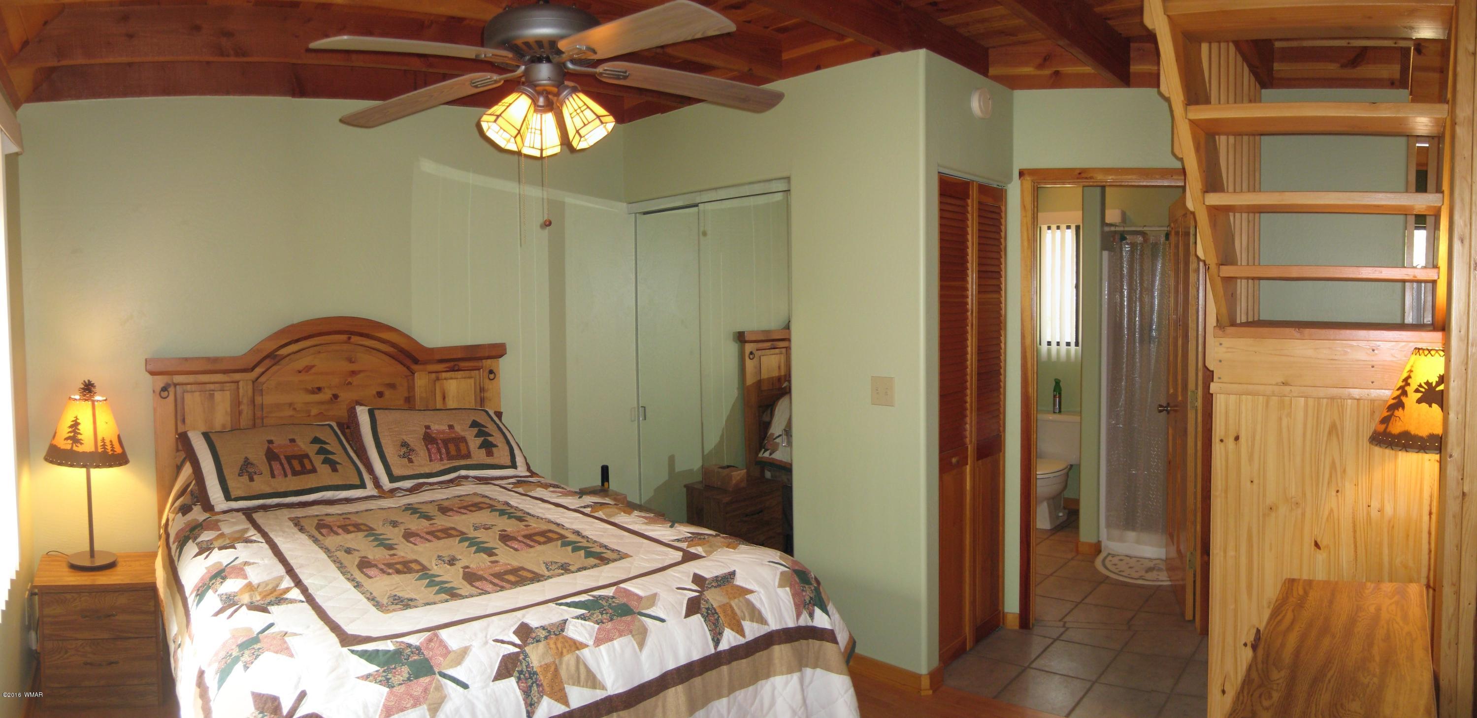 2845 Markham Road Overgaard, AZ 85933 - Photo 38 of 56 a bedroom with a bed and a chandelier