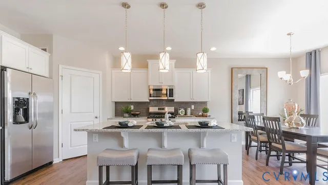 a kitchen with stainless steel appliances kitchen island granite countertop a dining table chairs and sink