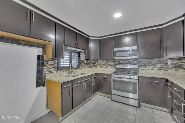 a kitchen with stainless steel appliances granite countertop a sink stove and cabinets