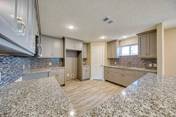 a large kitchen with stainless steel appliances kitchen island granite countertop a refrigerator and cabinets