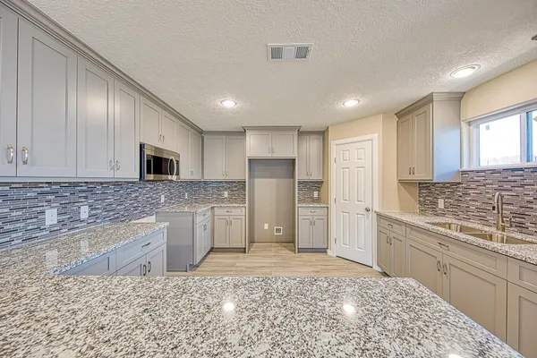 a kitchen with stainless steel appliances granite countertop a stove top oven a sink and a refrigerator