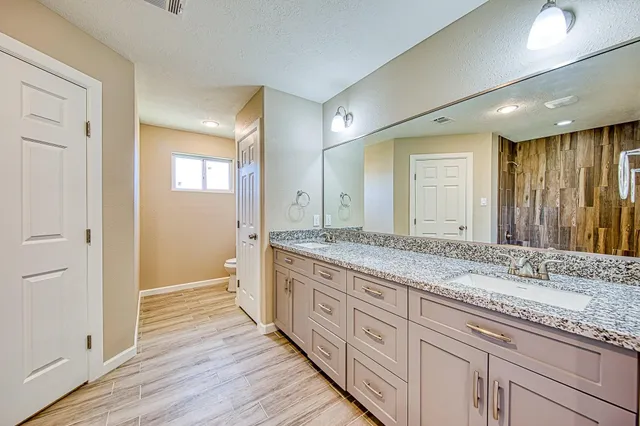 a bathroom with a granite countertop double vanity sink and a mirror