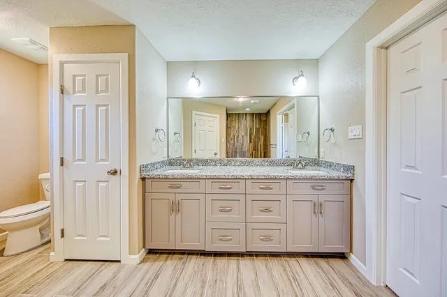 a spacious bathroom with a granite countertop sink toilet a mirror and a
