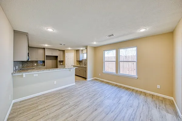 a large kitchen with stainless steel appliances granite countertop a refrigerator a sink dishwasher a stove and white countertops with wooden floor