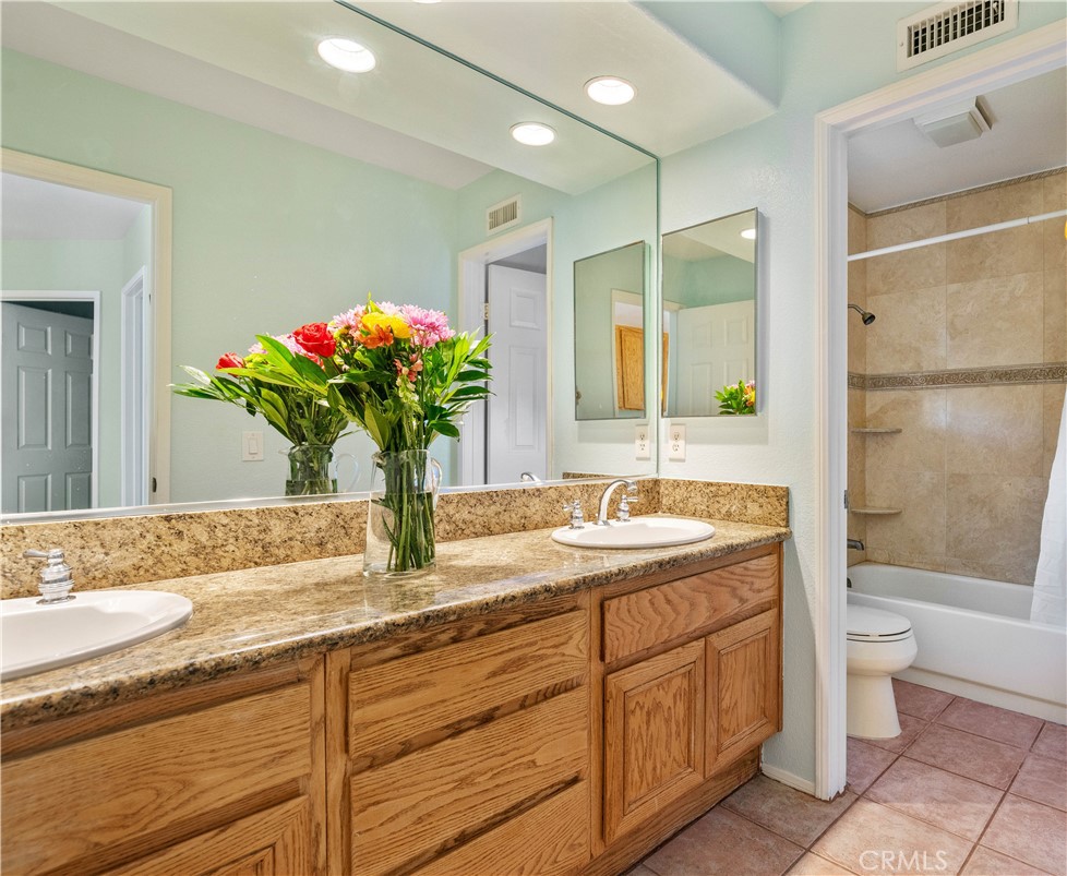 1147 Rosemary Circle Corona, CA 92879 - Photo 23 of 32 a bathroom with a granite countertop sink a large mirror and a bathtub