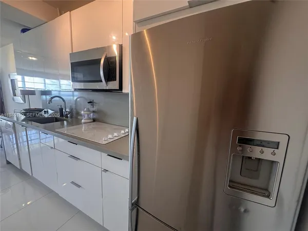 a kitchen with stainless steel appliances granite countertop a sink a microwave a refrigerator and cabinets