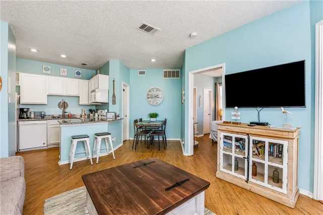a living room with stainless steel appliances furniture and a flat screen tv