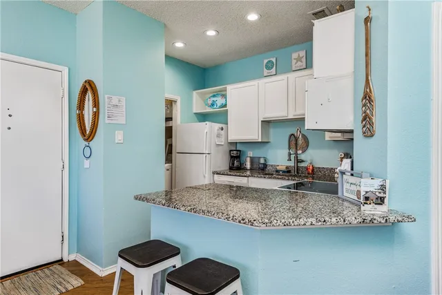 a kitchen with kitchen island granite countertop a sink a stove and a refrigerator