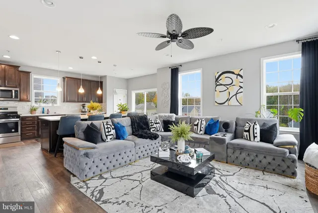 a living room with furniture kitchen view and a large window