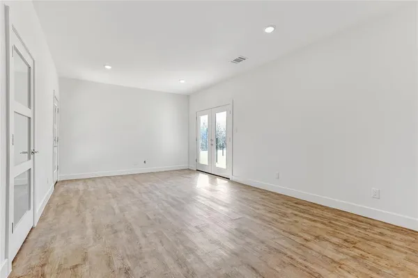 a view of an empty room with wooden floor and window