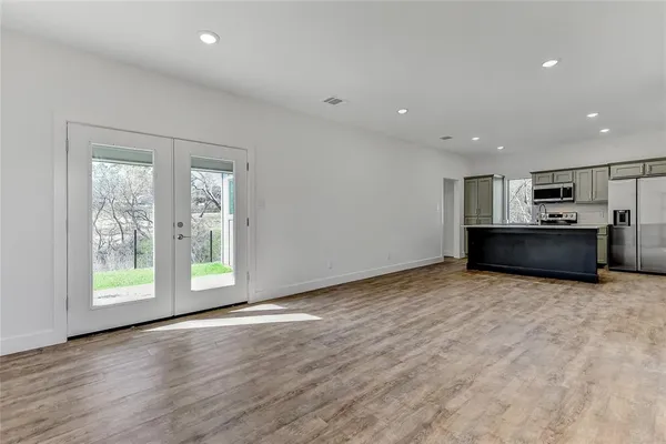 a view of an empty room with a window and wooden floor