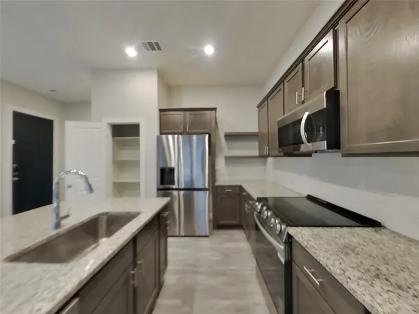 a kitchen with stainless steel appliances granite countertop a sink a stove and a refrigerator