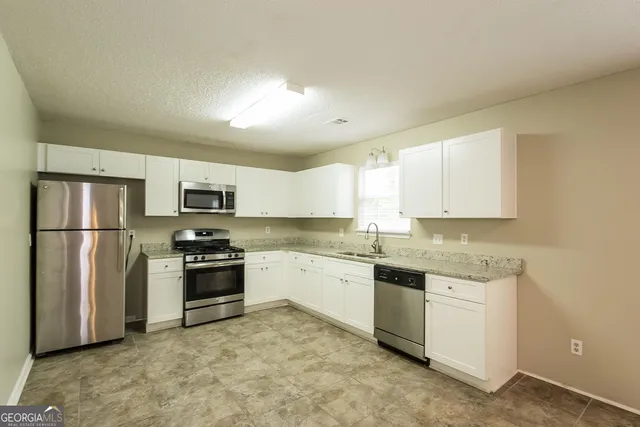 a kitchen with stainless steel appliances granite countertop a stove top oven a refrigerator a sink and dishwasher