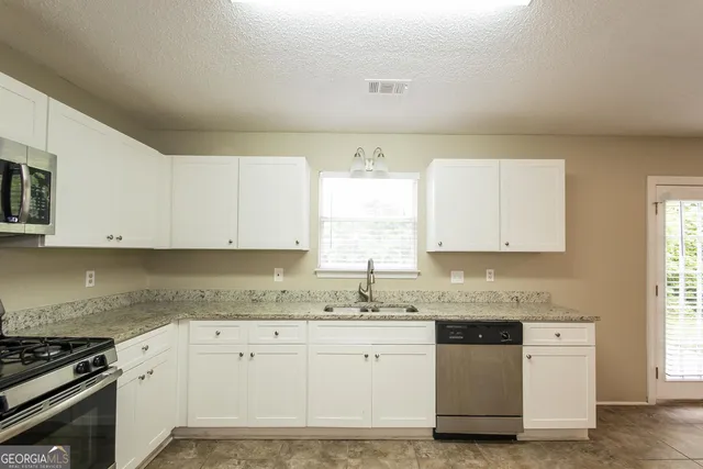a kitchen with granite countertop white cabinets sink and white appliances
