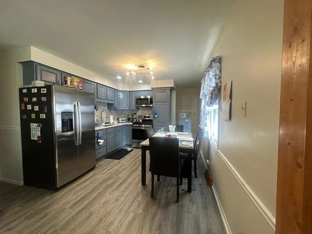 a kitchen with stainless steel appliances a refrigerator and a wooden floor