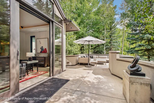 a view of a patio with chairs and a table and chairs under an umbrella