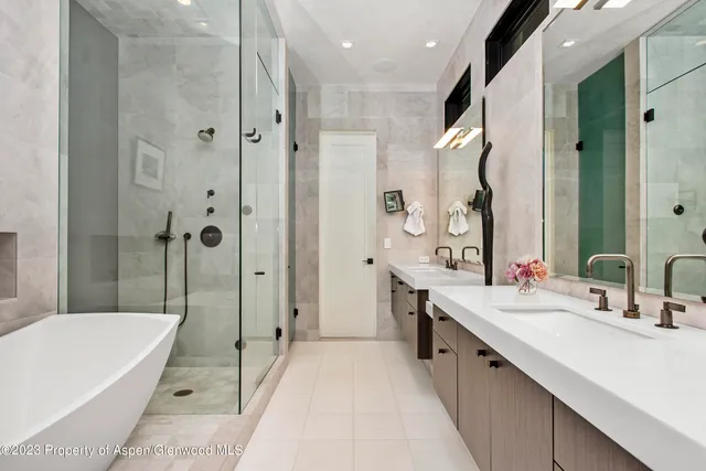 a bathroom with a double vanity sink a large mirror a bathtub and shower