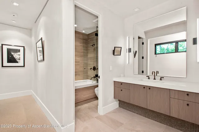 a spacious bathroom with a double vanity sink toilet mirror and bathtub