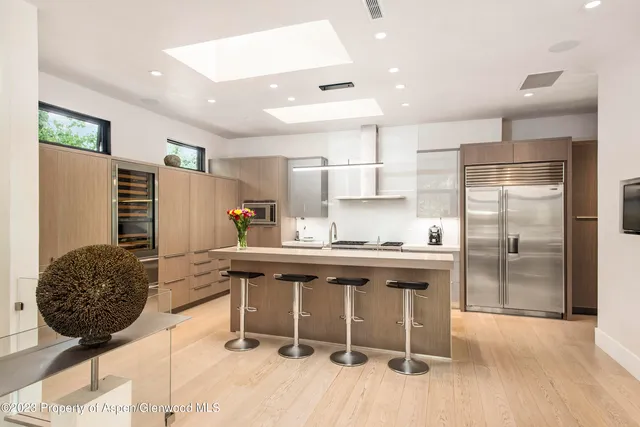 a kitchen with stainless steel appliances granite countertop a stove a sink a refrigerator and chairs