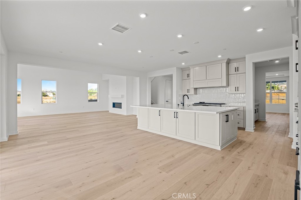 16642 Ginger Creek Drive Riverside, CA 92504 - Photo 17 of 22 a large white kitchen with kitchen island white cabinets and wooden floor