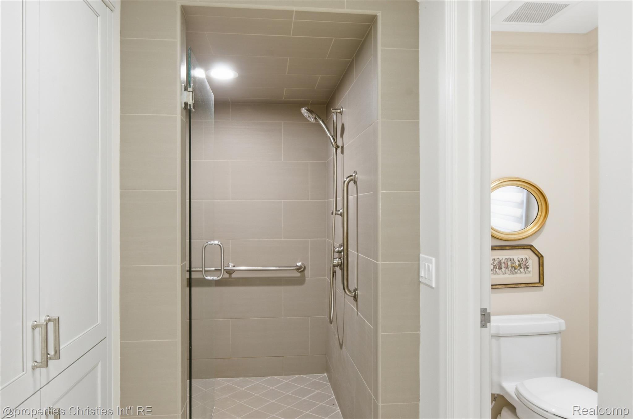 25235 Canterbury Road Franklin, MI 48025 - Photo 29 of 56 Walk-in shower featuring light-toned tile walls, glass enclosure, and a diamond-patterned tile floor