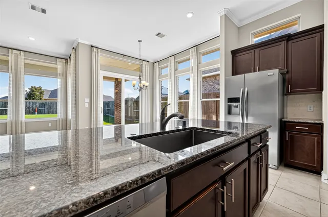 a kitchen with granite countertop a sink and refrigerator