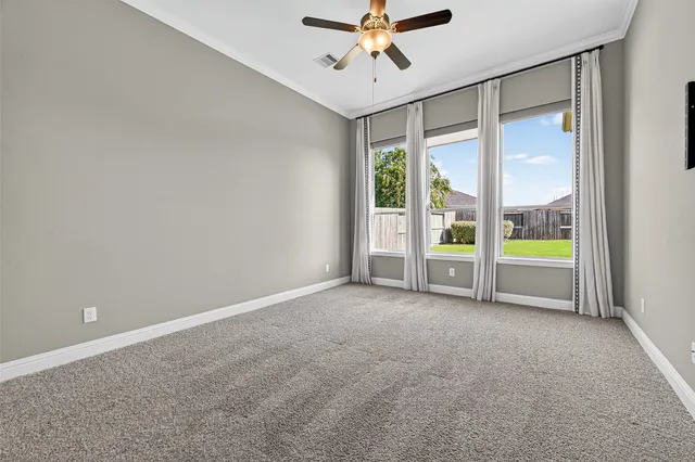 a view of an empty room with a ceiling fan and window