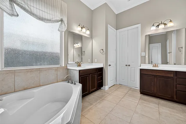 a bathroom with a sink a tub and a large mirror