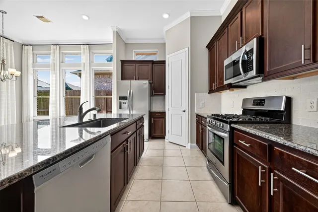 a large kitchen with stainless steel appliances granite countertop a stove and a refrigerator