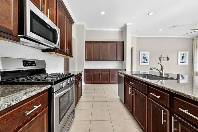 a large kitchen with stainless steel appliances granite countertop a stove top oven a sink dishwasher and microwave oven on the granite countertops