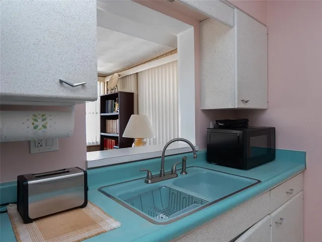a kitchen with sink a microwave and cabinets