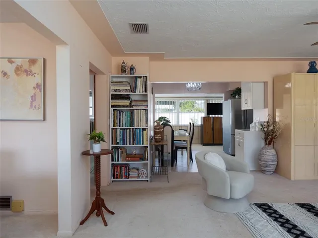 a living room with furniture a dining table and a refrigerator