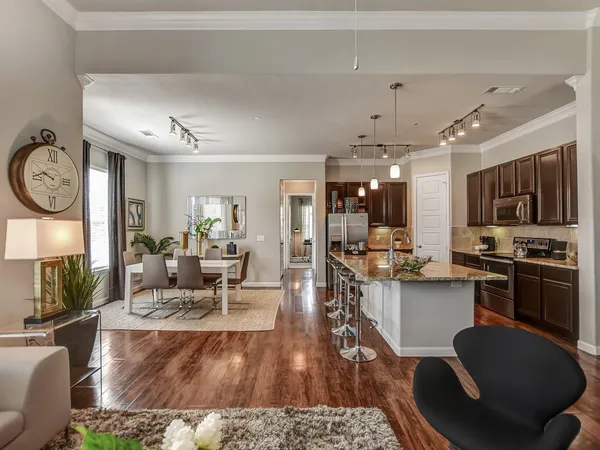 a living room with stainless steel appliances furniture a rug and a view of kitchen