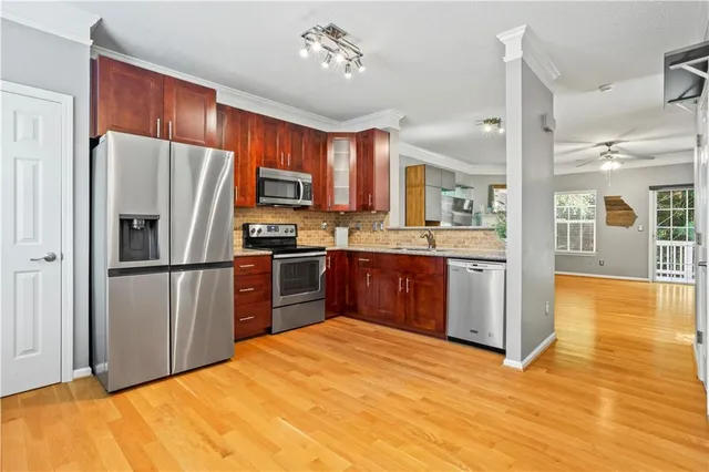 a kitchen with stainless steel appliances a refrigerator a sink dishwasher a oven with wooden cabinets and floor