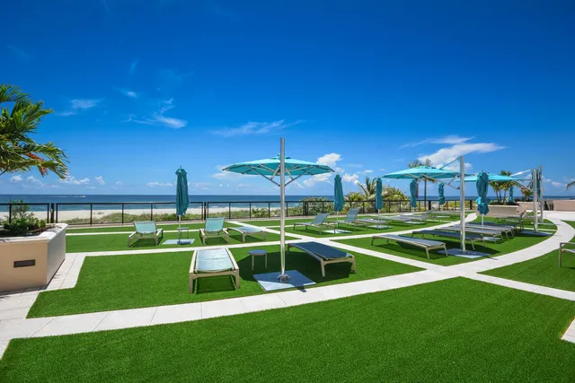 a view of a white house with a big yard and potted plants