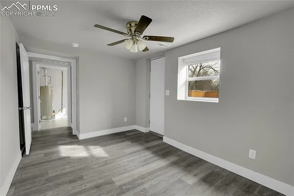 an empty room with wooden floor chandelier fan and windows